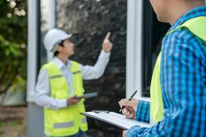 inspector or engineer inspecting construction and quality assurance new house using a checklist. Engineers or architects or contactor work to build the house before handing it over to the homeowner. photo