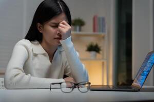 Eye problems, Asian women with tired and irritated eyes, eye rubbing, dry, eye pain after work, migraine, headache, blurred vision, photophobia, working in the dark. blue light from computer screens. photo
