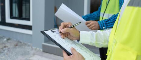 inspector or engineer is inspecting construction and quality assurance new house using a checklist. Engineers or architects or contactor work to build the house before handing it over the homeowner. photo