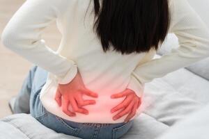 woman holding back while and suffer from unbearable pain health and problems, chronic back pain, backache in office syndrome, scoliosis, herniated disc. photo