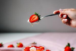 Fresh and healthy spoonful of yogurt and strawberry, isolated on a neutral background. A simple yet appetizing concept for food styling or nutrition content. photo