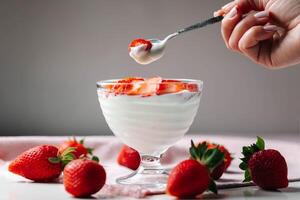 A person is holding a spoon over a bowl of yogurt photo