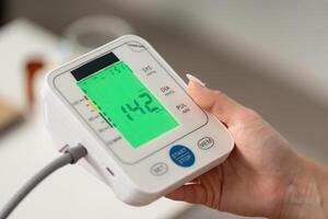 Health Monitoring. Individual checking blood pressure with digital monitor at home. photo