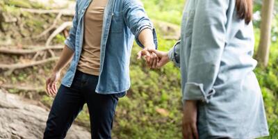 Couple holding hands in nature. Young man and woman sharing a moment of connection by a stream. photo