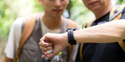 Father and Son Checking Time While Hiking. A father and son evaluating their hiking progress with a smartwatch. photo