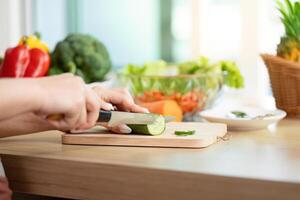 Wellness and Meal Preparation. Close-up of a woman slicing cucumber for a healthy dish. photo