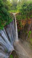 Cinematic FPV drone shot diving through the stunning multi-stream Tumpak Sewu waterfall, surrounded by lush rainforest cliffs in East Java, Indonesia. video