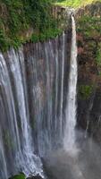 Aerial view of multi-stream Tumpak Sewu waterfall cascading into lush jungle canyon surrounded by green cliffs in East Java, Indonesia. video