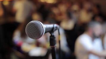 Close-Up of Microphone on Stage Before Public Speech, Audio equipment ready for performance in blurred crowd background video