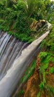 Cinematic FPV drone shot diving through the stunning multi-stream Tumpak Sewu waterfall, surrounded by lush rainforest cliffs in East Java, Indonesia. video