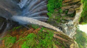 Epic FPV drone dive into powerful multi-stream Tumpak Sewu waterfall, deep green canyon, and lush rainforest in East Java, Indonesia. video