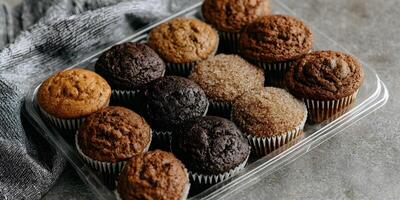 Assortment of Delicious Brown Sugar and Chocolate Muffins in Clear Plastic Container photo