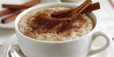 Closeup of Rice Pudding in White Mug with Cinnamon Sticks and Ground Cinnamon photo