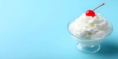 Vanilla Ice Cream Sundae with Whipped Cream and Cherry Garnish in Glass Bowl on Blue Background photo