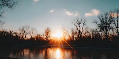 Sunset over Frozen River Winter Landscape Bare Trees Orange Sky photo