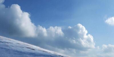 Snowy Hillside Under Blue Sky with Rain Clouds photo