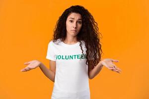 I Don't Know. Clueless Volunteer Lady Shrugging Shoulders Looking At Camera Posing Standing On Yellow Studio Background. Portrait Of Puzzled Female Activist Concept photo