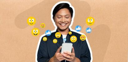 Asian man with a joyful expression is absorbed in his smartphone, chatting and interacting on social media. Emoticons float around, highlighting his cheerful activity. photo