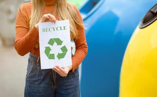 Woman Holding Placard With Green Recycle Sign Standing Near Different Colorful Garbage Containers For Trash Sorting, Unrecognizable Lady Agitating For Zero Waste Living, Cropped Image, Free Space photo