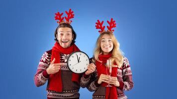 New Year celebration. Affectionate young couple with champagne and clock showing five minutes till midnight, blue background photo