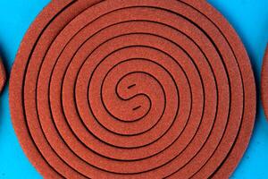 A mosquito coil in a spiral shape on a blue background. Insect repellent for outdoor and indoor use, designed to keep mosquitoes away and provide protection from bites. photo