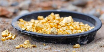 Gold Nugget Pile in Black Pan on Sand Beach photo