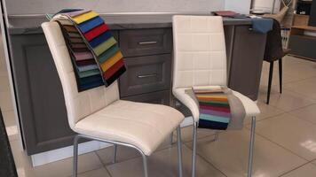 Two chairs stand with samples of textiles for the manufacture of upholstered furniture. custom furniture manufacturing store video