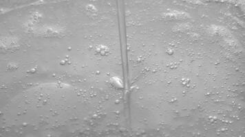 Thin trickle of transparent cosmetic gel with tiny bubbles flows down to the surface. Transparent liquid gel background, transparent serum texture. Cosmetic skin care product. video