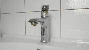 Water is dripping from a damaged faucet. The old faucet was covered with lime scale due to poor water quality and hard water. Useless use of water. video