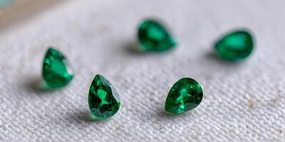 Five Pear Shaped Emerald Gemstones on White Fabric Close Up photo