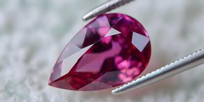 Closeup of Pink Pear Shaped Gemstone in Tweezers photo
