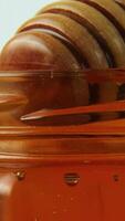 Honey dipper rotating slowly in thick golden honey creating swirling patterns video