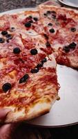 Enjoying Delicious Pizza topped with Olives and Other Toppings Freshly Served Hot. tempting pizza with melted cheese, and various meats, perfect for sharing with friends. vertical shot, film look video