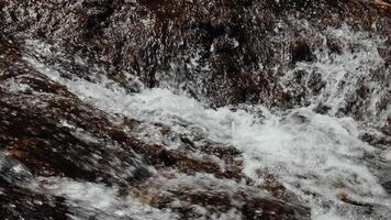 Flowing water cascading over rocky surfaces, creating mesmerizing whitewater patterns in pristine mountain wilderness landscape. Cascading water flowing over rocky terrain, generating patterns video