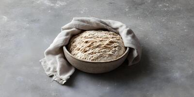 Artisan Bread Dough Rising in Bowl Covered with Linen Cloth on Concrete Background photo