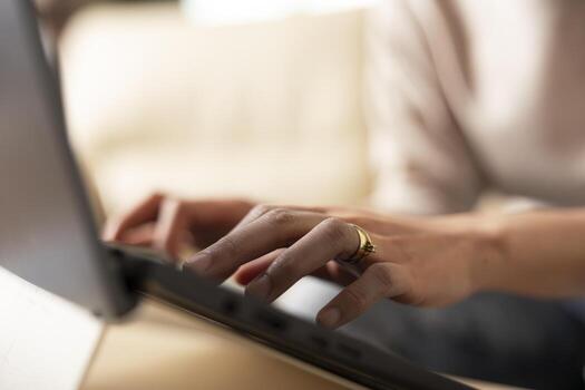 Close up of female hands typing on laptop keyboard, replying to work emails from home. Selective focus showing remote work routine with individual updating business reports and project proposals. photo