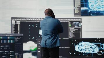 Preto programador especialista noivando dentro Programas desenvolvimento às uma Alto tecnologia área de trabalho, focado em grande dados painel. exibindo codificação vida e isto algoritmos dentro a tecnologia mundo. Câmera uma. video