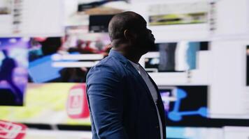 African American professional browses high tech environment with app icons, infographics and social networking feeds. Showcases big data on social media platforms, digital influence. Camera B. video