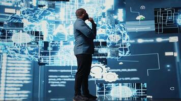 Black male specialist engaged in AI research interacting with data structures or platforms and smart technology systems. Studies deep learning, cloud computing and predictive analytics. Camera A. video