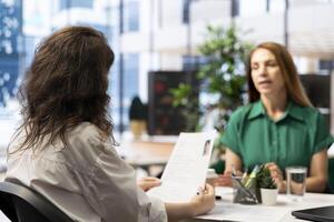 Manager interviewing worker, recruiting for job, discussing business offer in corporate office. Businesswoman hiring candidate after checking CV resume, recruitment concept photo
