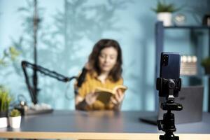 Close up of phone used by woman being sponsored by partnering publisher to do new book unboxing content. Focus on smartphone used by influencer to do new author novel product placement photo