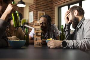 Diverse friends in fits of laughter, exchanging jokes and enjoying snacks and drinks during lively, joyful conversation. Happy multiethnic group laughing heartily and bonding over funny stories. photo