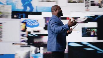African american public speaker discussing with audience about social media platforms, dynamic screens for entertainment and web communication. Networking advice for engagement. Camera A. video
