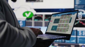 Black business manager using his laptop to examine fintech insight, reading big data and KPI metrics in order to build a new vision. Leadership and management skills. Close up. Camera B. video