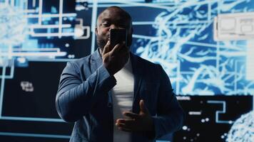 Young black businessman having a conversation on phone call, sharing insight on artificial intelligence systems and machine learning. IT engineer chatting about neural networks. Camera B. video