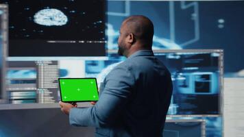africano americano isto especialista mostra tábua com croma chave tela e terminal janela dentro a fundo, digital transformação. exibindo Programas desenvolvimento com dados Ciência. Câmera uma. video