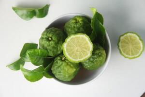 Kaffir lime or bergamot fruit, kaffir lime or citrus hystrix fruit in a white bowl and on a white background isolated photo