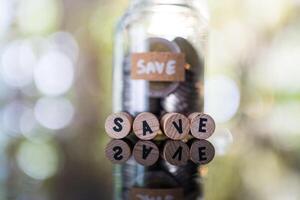 Wooden blocks displaying SAVE in font of glass jar bank fill with coin, symbolizing financial save and growth photo