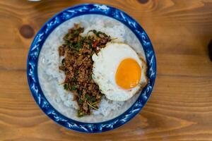 Stir fried minced beef with garlic and basil leaf in chilli sauce with cooked rice topped with runny fried egg photo