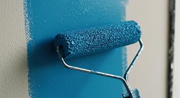 Painting Wall with Blue Color Using a Paint Roller Close Up photo